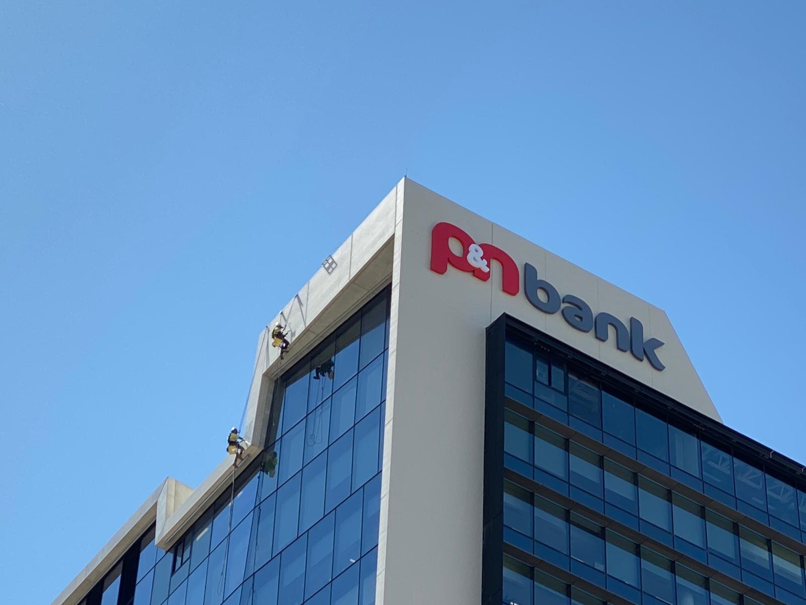Rope-access painter at height on a commercial tower facade