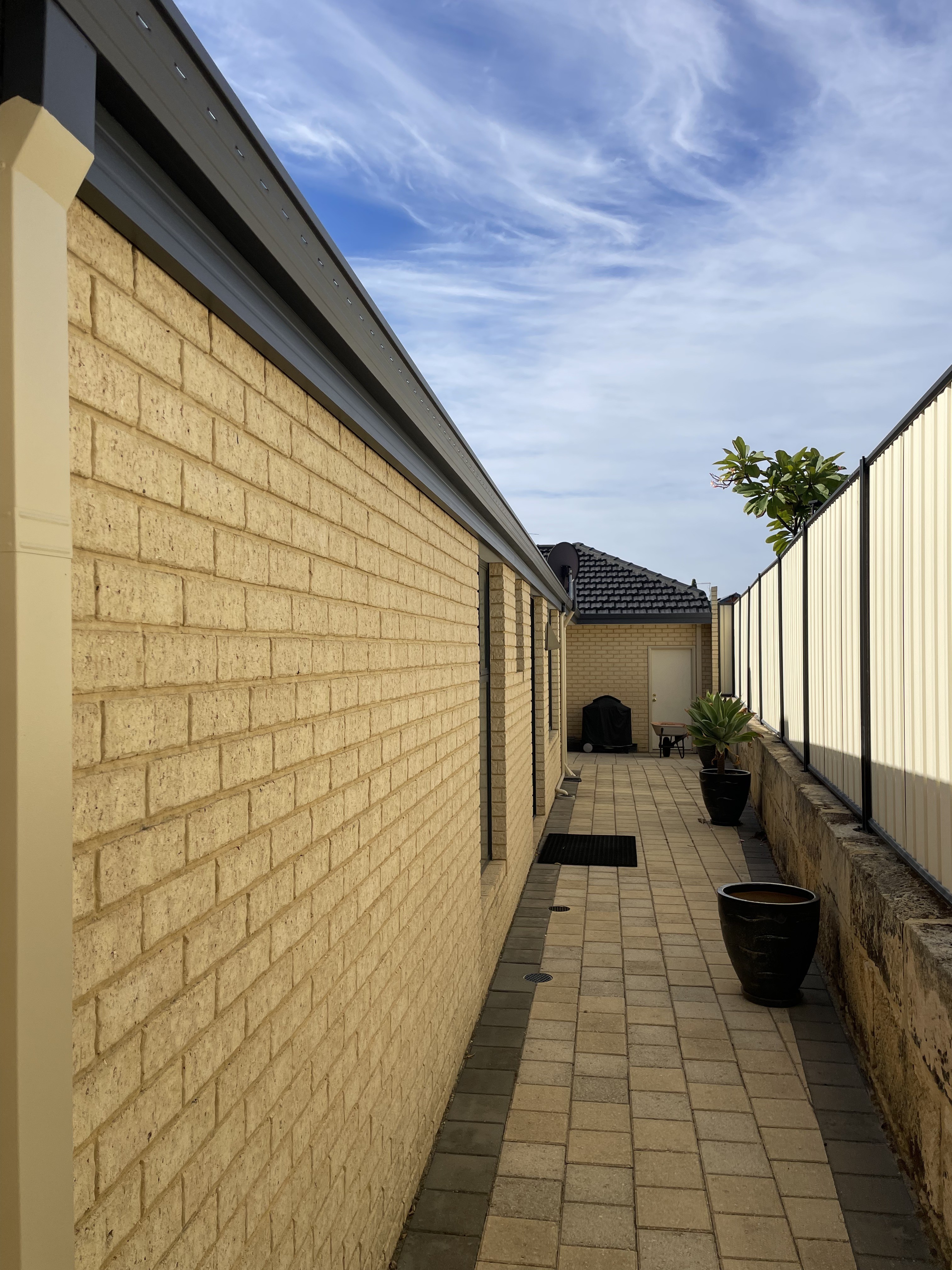 Painted gutter, fascia and downpipe along a brick exterior